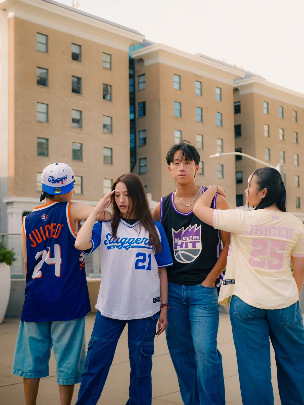 Four people wearing Sluggers Hit jerseys and a cap, outside in daylight